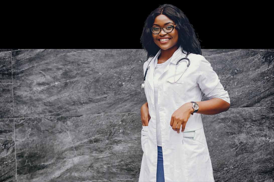 A smiling doctor in a white coat with a stethoscope standing against a stone wall